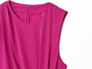 Detail of fuchsia sleeveless dress with pleated front and round neckline texture