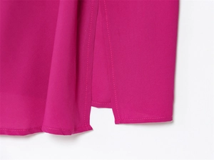 Detailed close-up of the bright magenta dress hem featuring a side slit and fine stitching