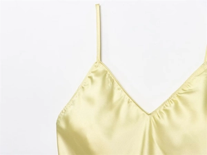 Détail d'un caraco en satin jaune pâle à bretelles spaghetti, texture soie et col en V
