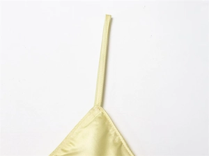 Gros plan des fines bretelles et de l'encolure sur la robe en satin couleur champagne