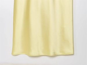 Gros plan de l'ourlet en satin jaune pâle montrant la texture soyeuse et les coutures