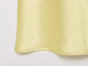 Vue macro de l'ourlet de robe en satin jaune clair avec couture fine et soie