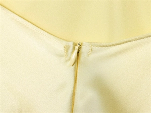 Détail de la fermeture éclair invisible sur une robe sans manches en satin jaune clair