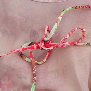 Close-up of pink floral chiffon fabric with a delicate bow tie detail and pattern