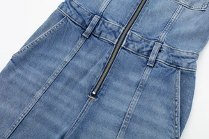 Vue détaillée de la fermeture éclair en métal et coutures jaunes sur la combi en jean