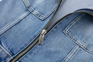Détail macro d'une fermeture éclair en métal doré et des doubles coutures sur le denim