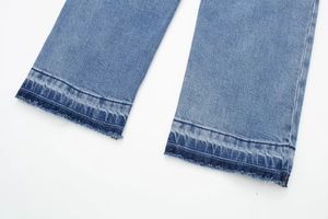 Détail de l'ourlet effiloché et du lavage denim bleu délavé sur une combinaison longue
