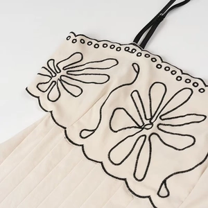 Details der Blumenstickerei auf den Stufenrüschen eines beigen Baumwoll-Sommerkleides
