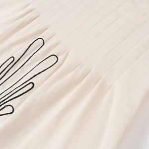 Nahaufnahme aus beigem Baumwoll-Leinen mit Falten und eleganter schwarzer Stickerei