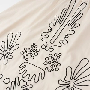 Detail der schwarzen Boho-Stickerei auf beige farbenem Baumwoll-Leinen-Stoff des Sommerkleids