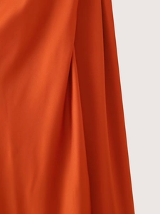 Detail von orangefarbenem Satinstoff mit glatter Textur und glänzendem Faltenwurf