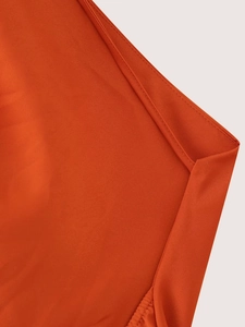Nahaufnahme der feinen Stofftextur und der sauberen Doppelnadel-Nähte an dem orangefarbenen Kleid