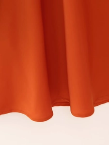 Nahaufnahme des orangefarbenen Satinkleides mit glatter Textur und feinen Nahtdetails