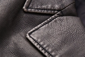 Close-up of fine grain texture and vintage stitching on a black faux leather vest
