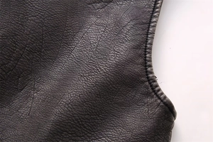 Close-up of black pebbled faux leather vest showing detailed stitching and edge binding