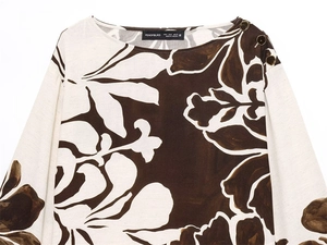 Detail of boat neck top with vintage metal buttons and dark floral print on beige fabric