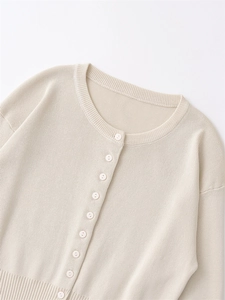 Detailed view of women's cream knit cardigan featuring round neck and buttoned front placket