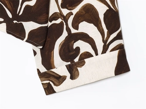 Macro detail of artistic floral print on textured linen fabric with neat hem stitching