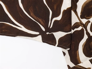 Macro detail of cotton linen floral fabric showing stitching and brown leaf pattern
