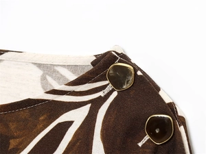 Macro shot of abstract floral shirt shoulder with gold-edged marble decorative buttons