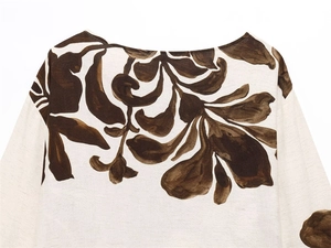 Close-up of floral print linen blouse featuring dark brown leaf patterns on cream fabric