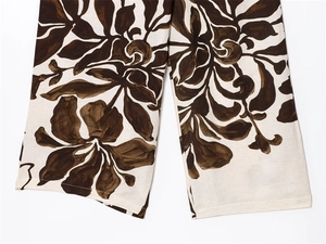 Detail of the stitched hem on beige floral linen pants with large dark brown flower prints