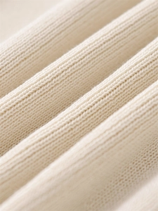 Close-up of beige ribbed knit fabric showing soft texture and premium vertical patterns
