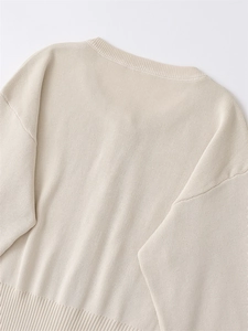 Detail view of the ribbed hem and back construction of a beige knitted cardigan