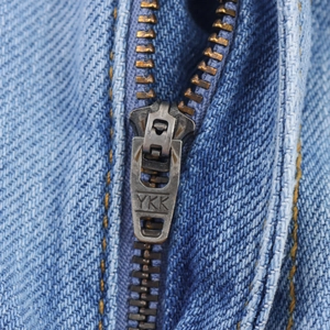 Macro-opname van hoogwaardige YKK metalen rits op een lichtblauwe denim spijkerbroek