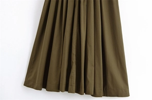 Dettaglio del tessuto plissettato di un abito midi verde oliva scuro con pieghe uniformi