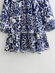Détail de robe florale bleue et blanche avec ourlet plissé et boutonnage frontal