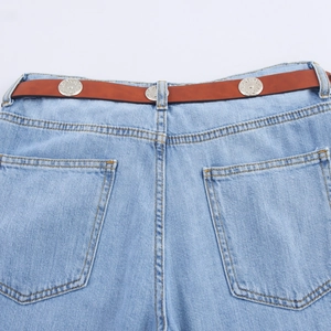 Detail van high-waist jeans met bruine leren riem en zilveren metalen gespen