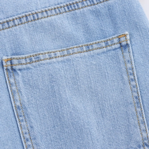 Detail van lichtblauwe denim met nauwkeurige gouden dubbele stiksels op de achterzak
