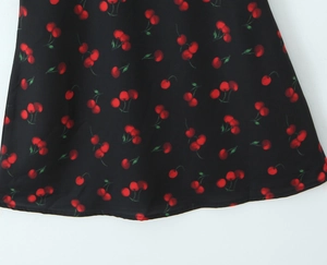 Vue détaillée de l'imprimé cerise sur tissu noir avec une finition d'ourlet soignée