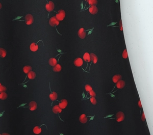 Gros plan sur tissu noir à imprimé cerise pour une robe licou moulante et sexy