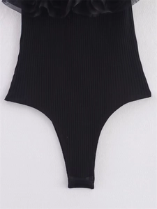 Détail du body noir côtelé avec bordure élégante en tulle superposé et volants décoratifs
