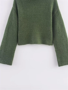 Detail of dark green knit sweater showing rib-knit cuffs and soft textured fabric