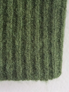 Close-up detail of green ribbed knit fabric showing soft wool texture and fibers