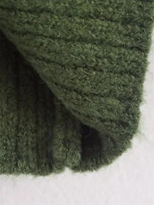 Detail shot of dark green ribbed knit sweater fabric showing soft wool texture