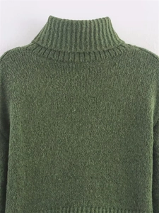 Detail of dark green knit sweater featuring thick ribbed texture and a high turtleneck collar