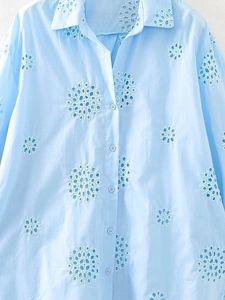 Nahaufnahme eines hellblauen Hemdes mit aufwendiger floraler Lochstickerei und Details