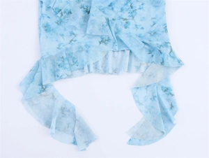 Detailansicht von hellblauem floralem Netzstoff mit elegantem Rüschensaum am Saum