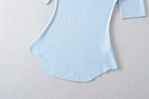 Detail of slim fit light blue ribbed knit top showing curved hem and smooth sleeve stitching