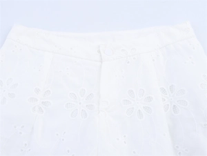Detailed close-up of white low-rise shorts featuring floral embroidery and eyelet lace
