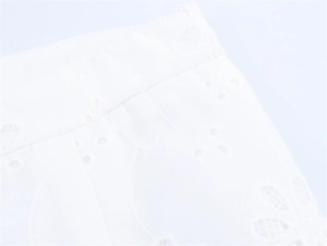 Detail of white low-waist shorts featuring floral embroidery and eyelet texture