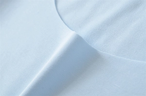 Close-up of light blue fine-knit cotton fabric neckline with high-quality seamless stitching
