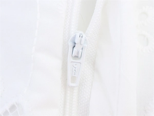 Close-up of white embroidered fabric with a high-quality zipper and engraved branding