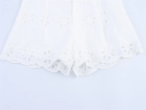 Macro shot of white daisy eyelet embroidery and scalloped hem on summer shorts