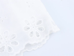 Close-up of white floral eyelet embroidery and elegant scalloped edge on fabric