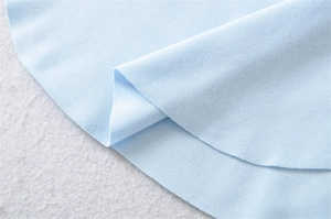 Macro shot of high-quality light blue knitted fabric showing smooth texture and softness